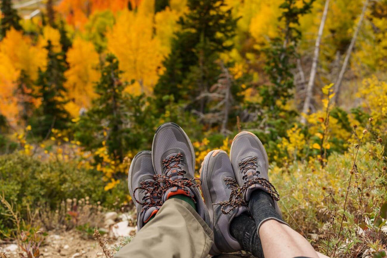 Couple aventureux profitant de la saison d'automne au sommet d'une montagne, portant des chaussures ATOM Trail pour la randonnée.