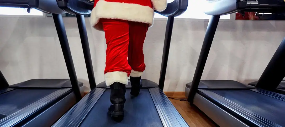 Père Noël en costume jogging sur tapis roulant