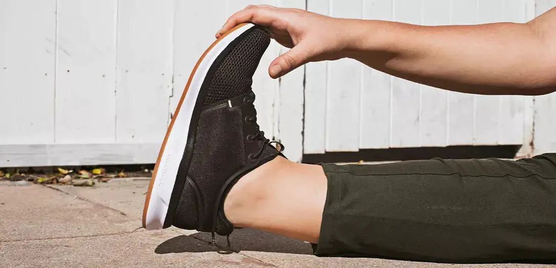 woman stretching wearing black sneakers