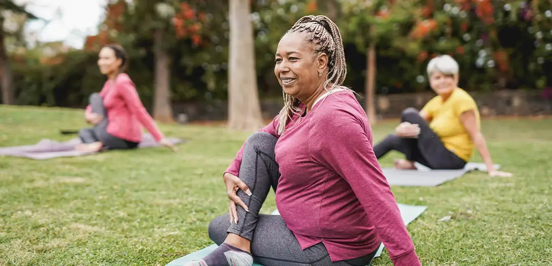 women practicing yoga at park