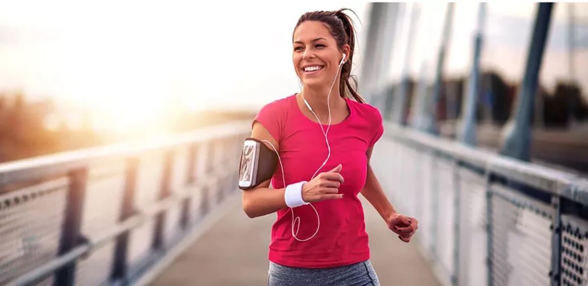 Woman in running attire jogging across a bridge.