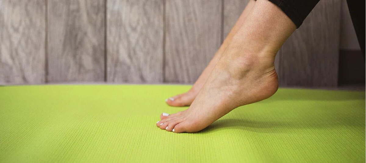 woman stretching feet and ankles on yoga mat