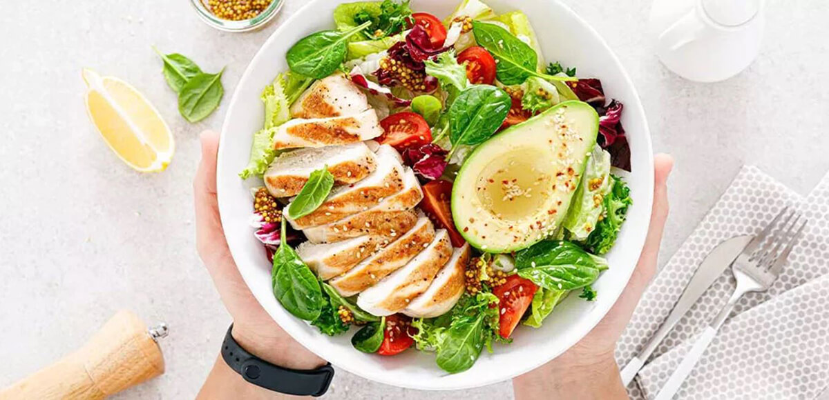 man holding bowl of nutritious chicken salad