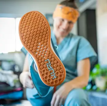 Nurse showing the bottom of their KURU shoes for physical therapists.