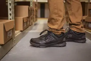 Man in a warehouse wearing black KURU shoes.